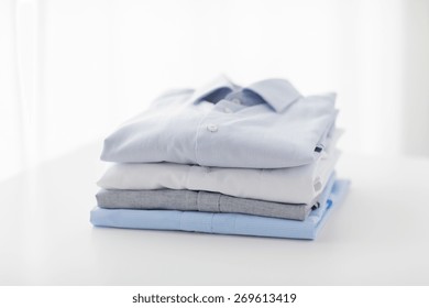 Ironing, Laundry, Clothes, Housekeeping And Objects Concept - Close Up Of Ironed And Folded Shirts On Table At Home