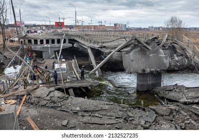 IRPIN, UKRAINE - Mar. 05, 2022: War in Ukraine. People cross a destroyed bridge as they evacuate the city of Irpin, northwest of Kyiv, during heavy shelling and bombing