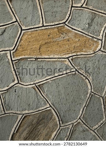 Irregular stone mosaic wall texture with yellow accent