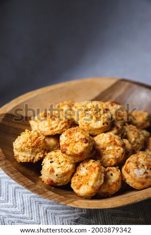Irresistible baked cheese crackers with flaked salt and black pepper in a wooden bowl for snacking.