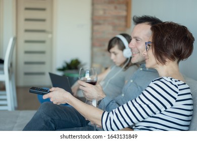 Irresponsible Parents Ignoring Lonely Daughter. Bored Young Girl Using Laptop On Bed While Mom And Dad Watching TV And Not Paying Attention To Her