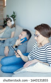 Irresponsible Parents Ignoring Lonely Daughter. Bored Young Girl Using Laptop On Bed While Mom And Dad Watching TV And Not Paying Attention To Her