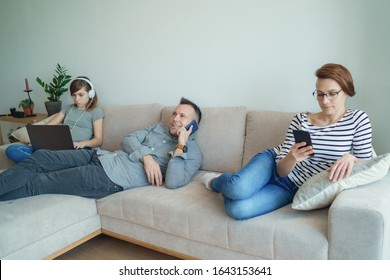 Irresponsible Parents Ignoring Lonely Daughter. Bored Young Girl Using Laptop On Bed While Mom And Dad Watching TV And Not Paying Attention To Her