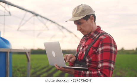 irrigation agriculture. a male farmer works on a laptop in a field with corn. irrigation agriculture business concept. lifestyle farmer scientist studying corn . healthy natural foods concept - Powered by Shutterstock