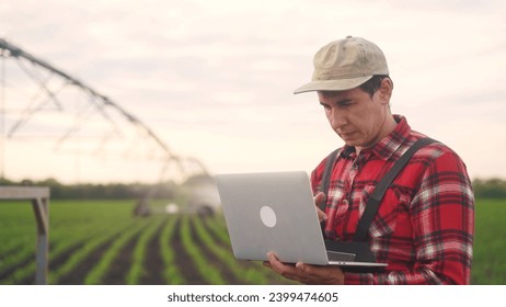 irrigation agriculture. a male farmer works on a laptop in a field with corn. irrigation agriculture business concept. farmer scientist lifestyle studying corn . healthy natural foods concept - Powered by Shutterstock