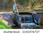 Irrigation concept, a small canal with little dam or water barrier for agriculture and farming in countryside of Holland, Dutch water management system, Netherlands.