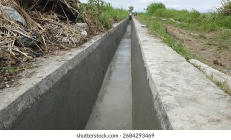 an irrigation or drainage channel made of solid concrete, functioning to channel agricultural irrigation water and manage rainwater or wastewater, built for long-term durability.