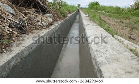 an irrigation or drainage channel made of solid concrete, functioning to channel agricultural irrigation water and manage rainwater or wastewater, built for long-term durability.