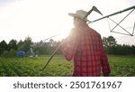 Irrigation. lifestyle farmer walks through a soybean field with. hoe. Agronomy agriculture young. concept. Irrigation watering field of. soybeans. Farmer walks through field of soybeans for irrigation