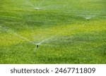 Irrigation sprinklers system. Photo with rotativ irrigating water sprinklers on a green grass lawn.