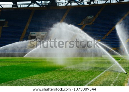 Irrigation turf. Sprinkler watering football field. System working on fresh green grass on football or soccer stadium.