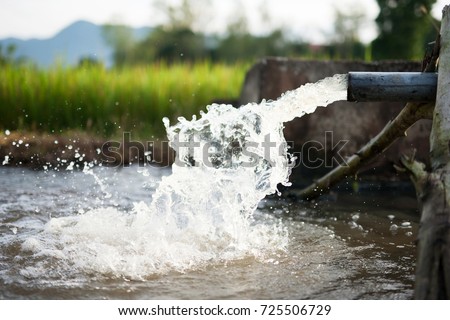 Irrigation water flow from pipe to canal for rice fields and agriculture