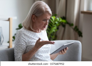 Irritated Aged 60s Woman Holding Broken Tablet Having Problems With Gadget, Need Help, Not Understand How Use Computer. Older Generation And Difficulties With Usage Of Modern Electronic Device Concept