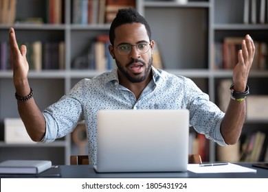 Irritated angry African American man wearing glasses having problem with broken laptop, confused unhappy businessman looking at screen, reading bad news in email, loss information or malware apps