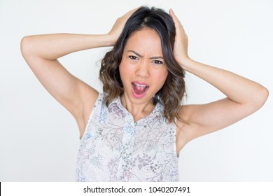 Irritated Asian woman surprised with bad news and clutching head. Upset young lady suffering from headache. Bad news or disease concept - Shutterstock ID 1040207491