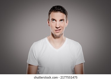 irritated and doltish man with nonsensical face expression look at top corner and show his confused emotions - Shutterstock ID 2177551475
