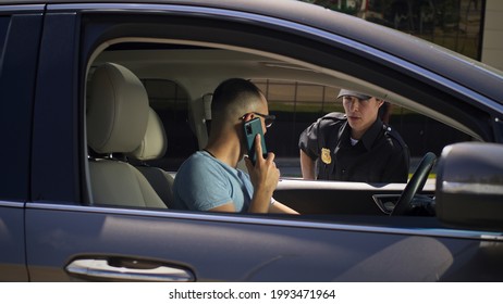 Irritated Driver With Smartphone Speaking With Police Officer