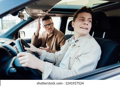 Irritated Father Teaching Smiling Teen Son Driving Car