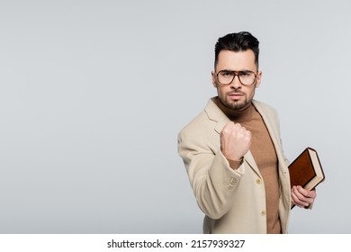 irritated literary critic with book showing clenched fist isolated on grey - Shutterstock ID 2157939327