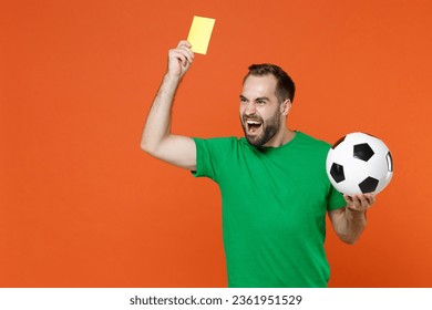 Irritated man football fan in green t-shirt cheer up support favorite team with soccer ball propose player retire from field hold yellow card isolated on orange background. Sport leisure concept - Powered by Shutterstock