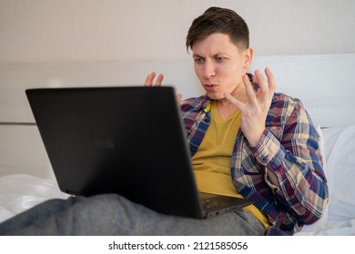 Irritated Man Sitting On Bed Looking At Laptop Screen, Arms Outstretched, Feeling Angry And Embarrassed, Having Problems With Broken Computer, Reading Bad News In Email, Lost Information, App Crash