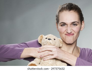 irritated young woman strangling her teddy bear for jealousy or teenager crisis