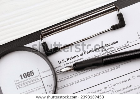 IRS Form 1065 US Return of Partnership Income blank on A4 tablet lies on office table with pen and magnifying glass close up