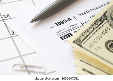 IRS Form 1095-A Health Insurance Marketplace Statement Tax Blank Lies With Pen And Many Hundred Dollar Bills On Calendar Page