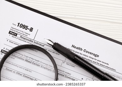 IRS Form 1095-B Health Coverage tax blank on A4 tablet lies on office table with pen and magnifying glass close up