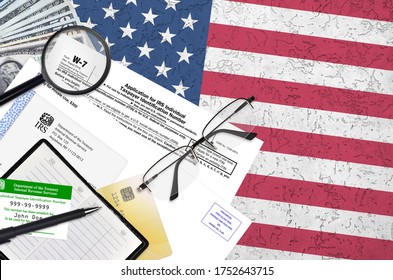 IRS form W-7 Application for IRS individual taxpayer identification number lies on flat lay office table and ready to fill. U.S. Internal revenue services paperwork concept