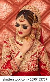 Islamabad. Pakistan January 4th 2021. Pakistani Indian bride dressed in  red traditional wedding clothes sari embroidered with gold jewelry.