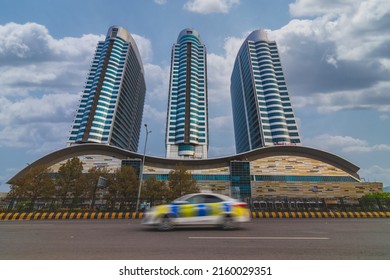 Islambad Pakistan May 2022, Famous Landmark Of Islamabad Pakistan, Centaurus Mall With  Trail Of Car Early Morning, Blue Sky. Islamabad Police Car Passing In Front Of Centaurus Mall