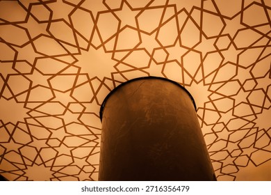 Islamic geometric pattern ceiling light inside a mosque, featuring an elegant arabesque star design. The detailed symmetry and warm lighting highlight traditional Islamic art, spiritual architecture, and cultural heritage