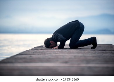 Islamic Man Praying On A Wooden Pier In Dusk