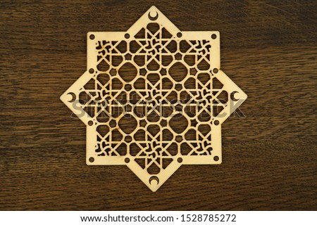 Islamic patterns. crescent moon  with laser carved woods on brown wooden background . 