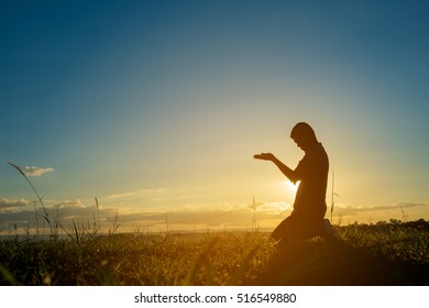 Islamic religion. Silhouette of man praying at the sunset on a background blue sky