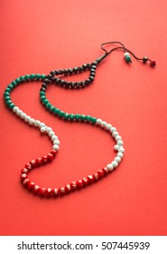 An Islamic rosary with beads in national flag colors of UAE on red background. Top view.