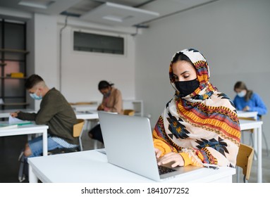 Islamic student with face mask at desks at college or university, coronavirus concept.