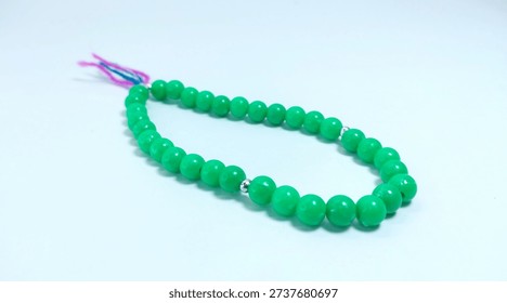 Islamic tasbih (string of prayer beads) made of green plastic material isolated on bright background.