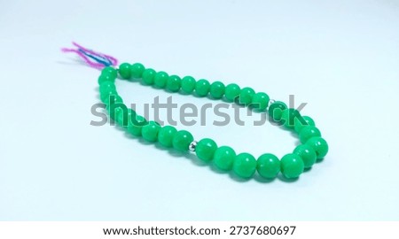 Islamic tasbih (string of prayer beads) made of green plastic material isolated on bright background.