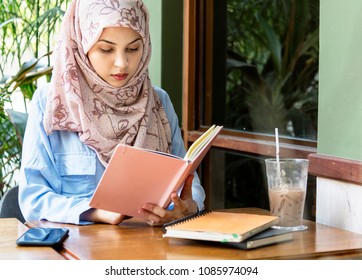 Islamic woman reading book at cafe - Powered by Shutterstock