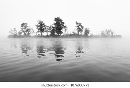 Island On The Water Viewed Through The Morning Fog. Black And White. 