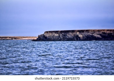 Islands In Arctic Ocean. Coast Of Island Vaigach Near Yugorski Shar Strait: Rocky Cliff And Tundra. Polar Zone, One Of Sites Northeast Passage At White Night (midnight Sun). Russia