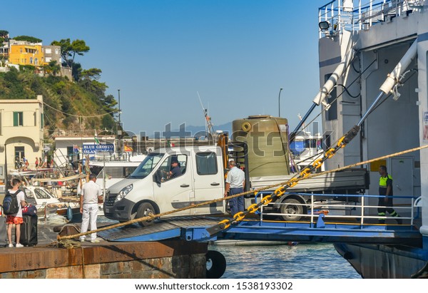 ISLE OF CAPRI, ITALY - AUGUST 2019: Truck with a\
large container on the back driving off a ferry in the port on the\
Isle of Capri.