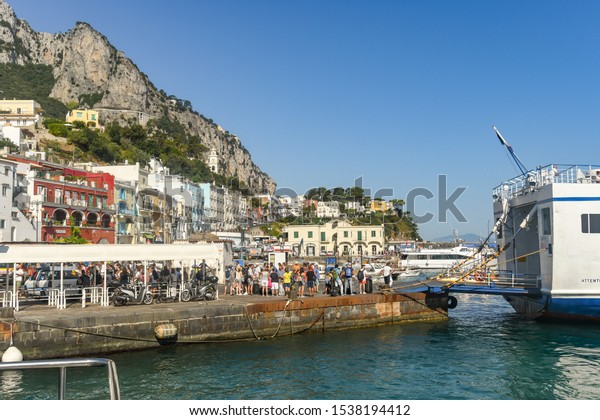 ISLE OF\
CAPRI, ITALY - AUGUST 2019: People waiting on the quayside to board\
a ferry in the port on the Isle of\
Capri.