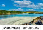 Isle of Eigg, Small Isles, Hebrides, Scotland.  A beautiful bay at low tide with silver sands, blue sea, blue sky and white fluffy clouds. Landscape, Horizontal, space for copy.