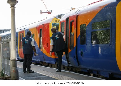 Isleworth, UK  August 1st 2022 
 Train Delay. Two Train Conductors Stand By A SWR Train Delayed By A Technical Problem In A Station And Communicate With The Driver