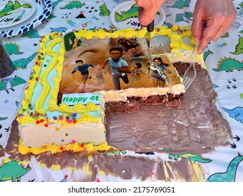 Islip Terrace, NY, USA, 6.26.22 - The Top Down, Close Up View Of A Jurassic World Birthday Cake That Is Being Sliced And Served On Dinosaur Cake Plates. The Ice Cream Cake Is Melting.