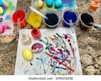 Islip Terrace, NY, USA, March 28, 2021 A Family Painting Easter Eggs With Crayola Paint. Dyed Eggs With A Rainbow Painted On, Colorful Paint Streaks, Dye Cups, Paint Brushes, And Paper Towels. 