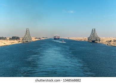 Ismailia, Egypt - November 5, 2017: El Ferdan Railway Bridge and container vessel ship MSC Maya passing Suez Canal in Egypt. Tugboat accompanies the ships.